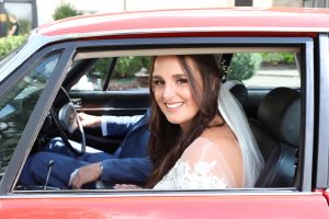 bride arrives at wedding in a red car
