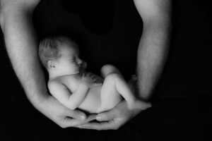 new born baby held in dads arms