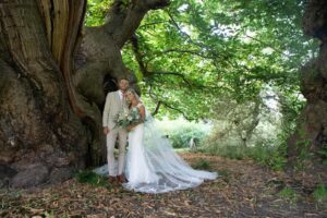 bride and groom by yew tree in doddington hall