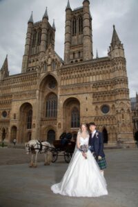 colour image of bride and groom outside lincoln cathedral with horse and carriage